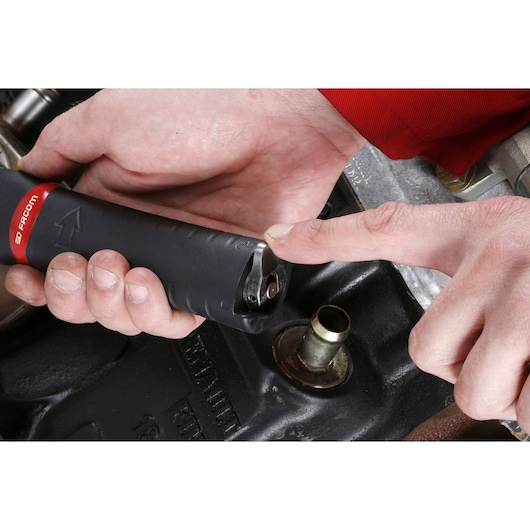 Photo of Facom U_48 tool handle with hand pointing at ratchet mechanism, automotive part background.