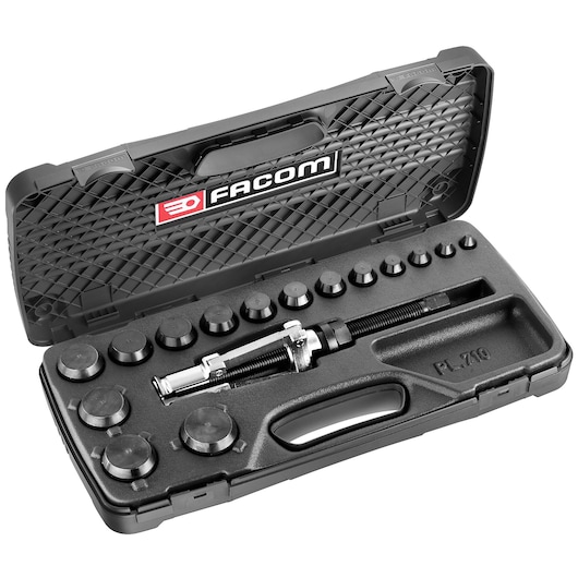 A black Facom-branded plastic carrying case containing an automotive tool set with various circular adapters and a central puller tool, neatly organized in fitted compartments.