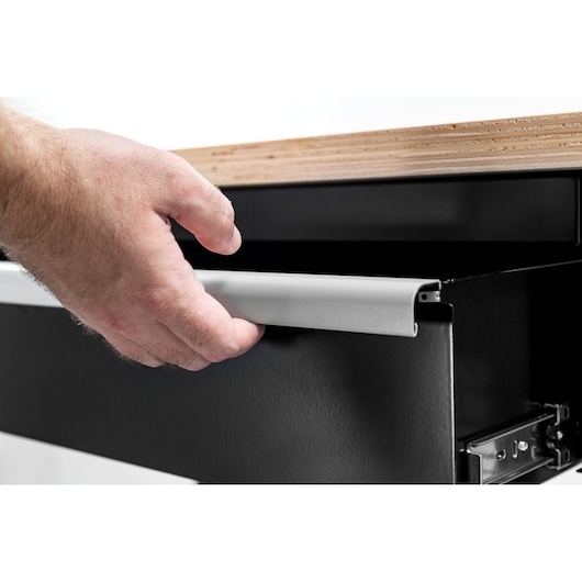 Facom WB2.1500W photography, close-up of hand opening black drawer under wooden workbench.