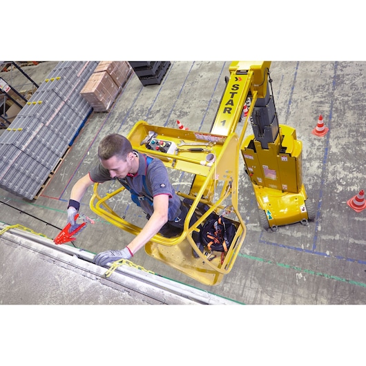 Facom WRT-DSLS tool set in use on aerial work platform, worker using pliers at height, warehouse setting, top-down view.